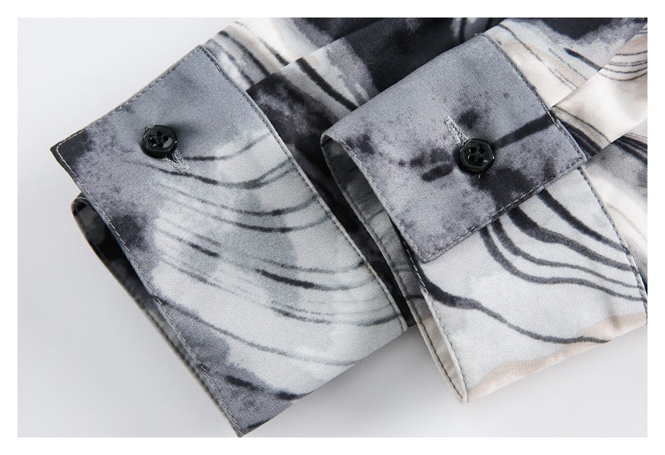 Close-up of two buttoned cuffs on a gray, black, and off-white abstract-patterned garment.