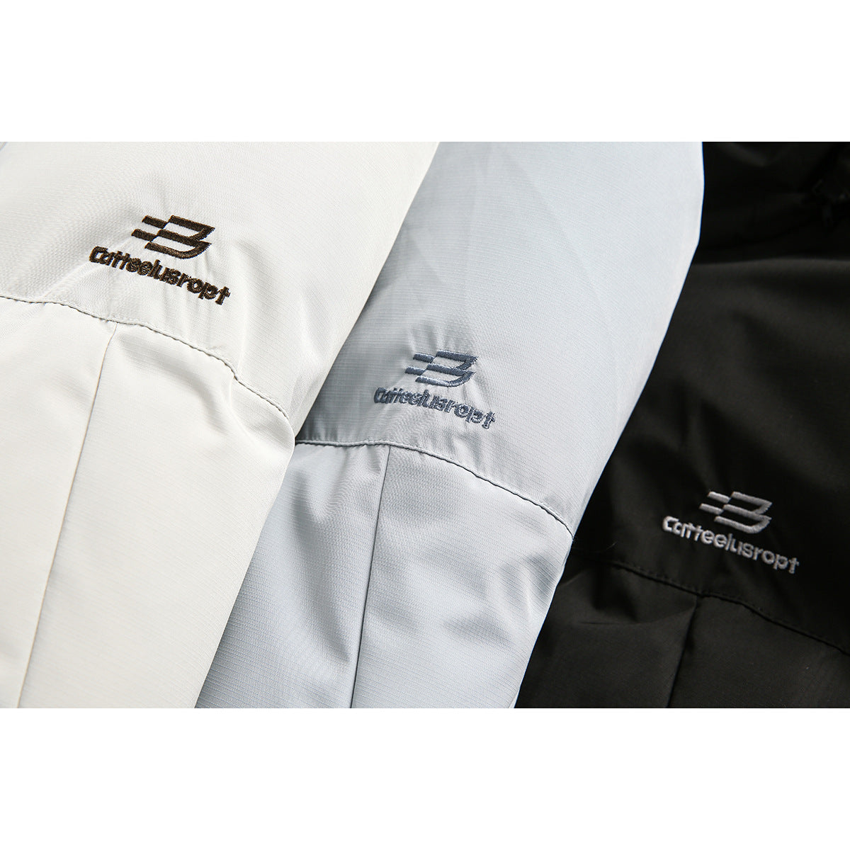 Close-up of embroidered logos on white, pale blue, and black jacket fabric.