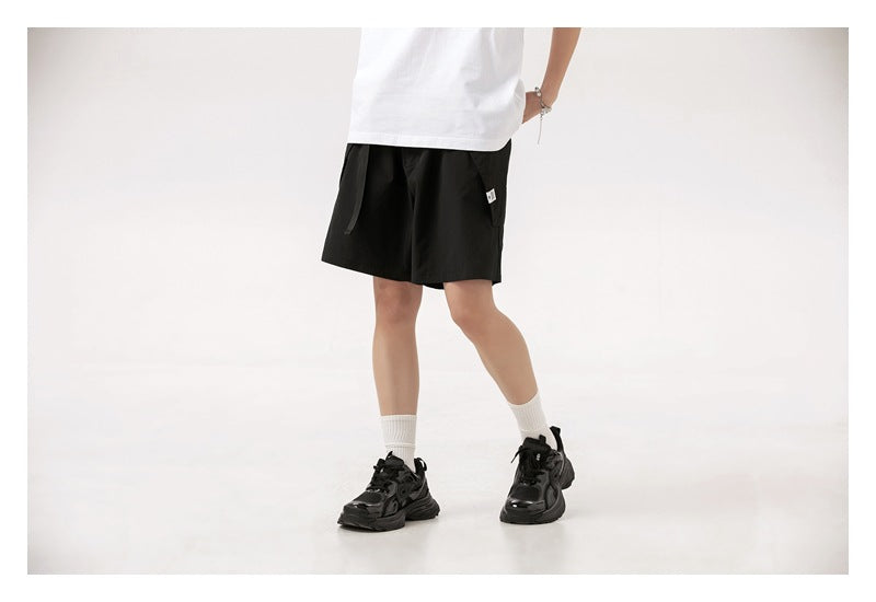 Cropped model wearing black drawstring shorts with side pockets, shown from the front.