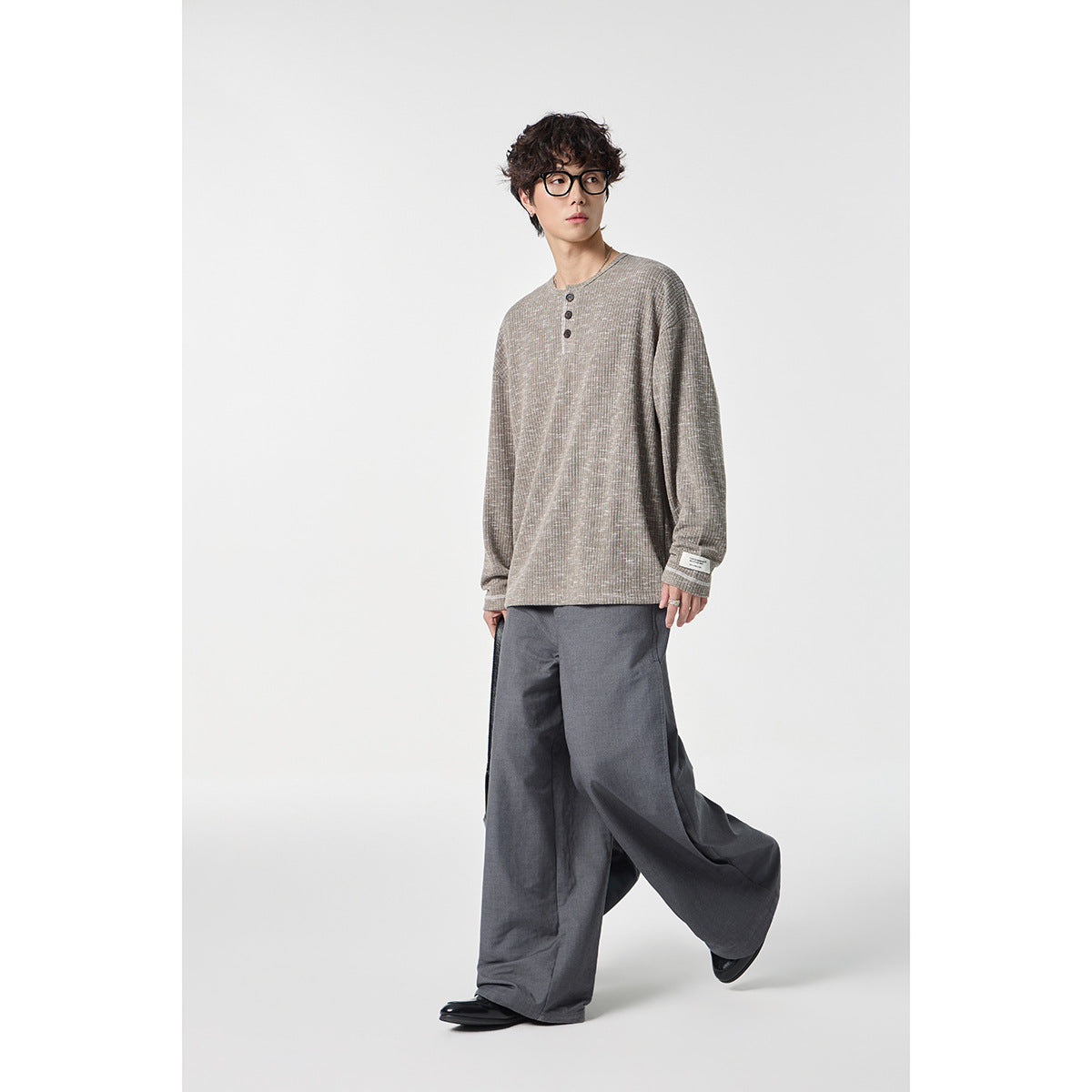 Model wearing a light beige heathered long-sleeve henley with gray wide-leg trousers.