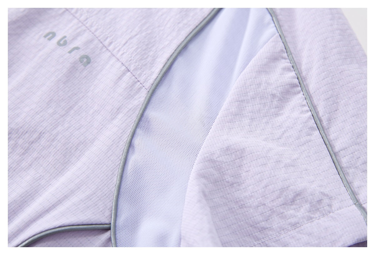 Close-up of a pale lilac top with a gray-piped mesh inset and subtle textured fabric.