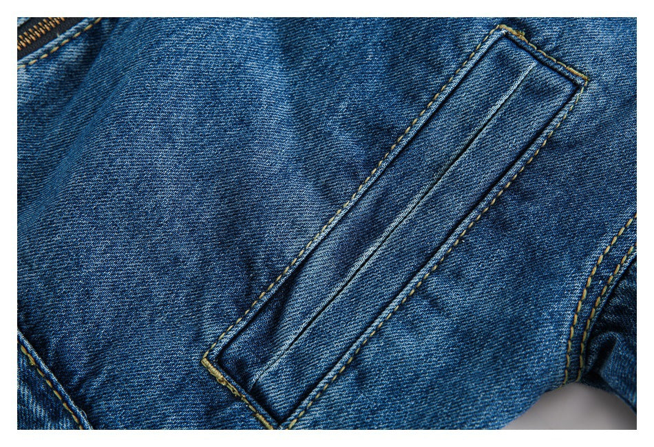 Close-up of a blue denim pocket opening and stitched panel with a zipper edge visible.