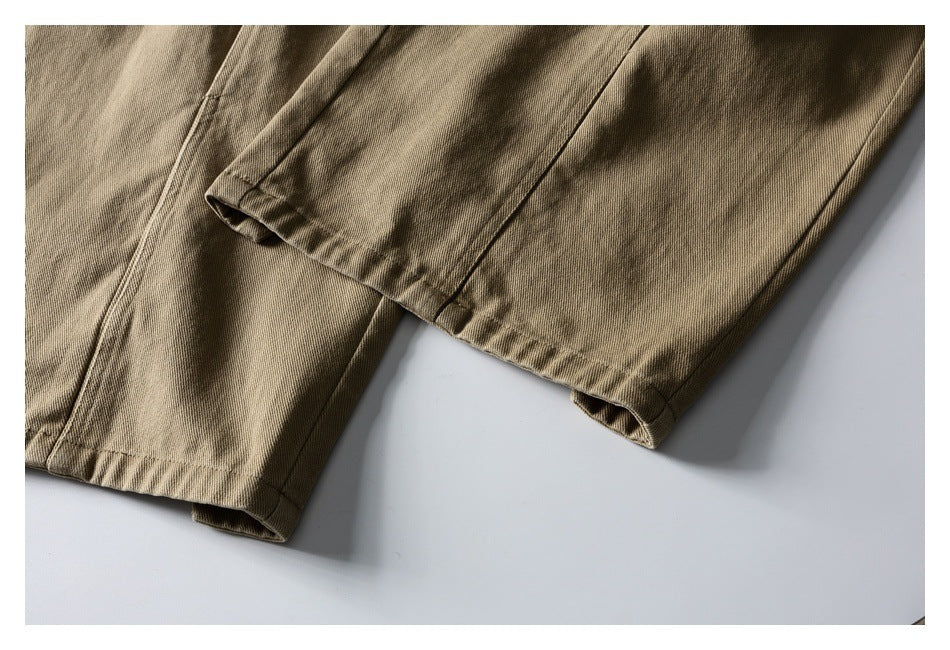 Close-up of tan trouser legs and stitched hems laid flat.