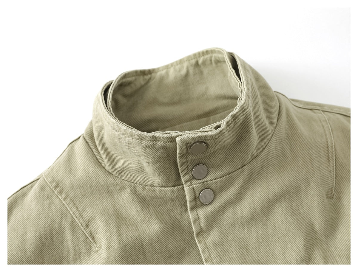 Close-up of a light khaki jacket's tall collar with three metal snaps.