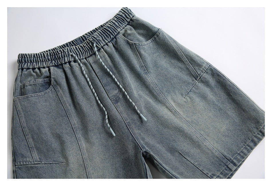 Front flat lay of gray-blue denim shorts with an elastic drawstring waist, roomy legs and large pockets.