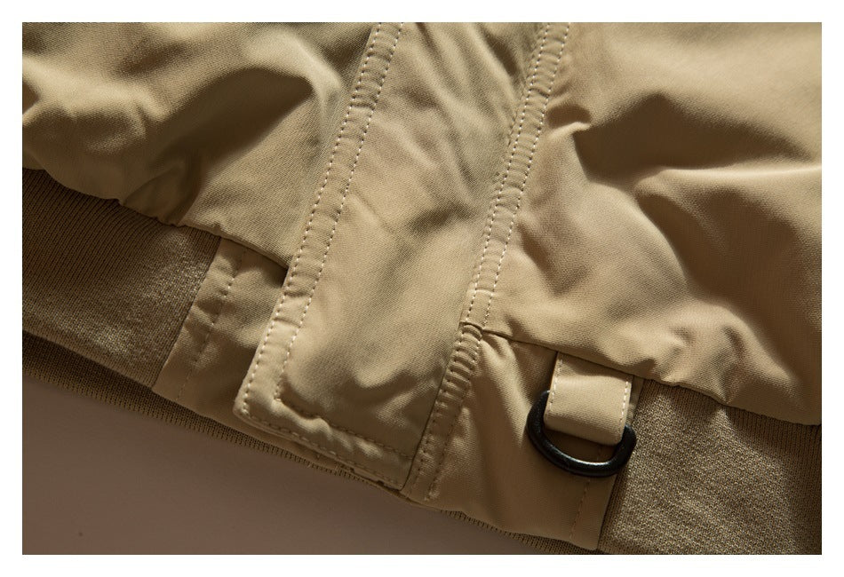 Close-up of a tan jacket seam with a stitched tab and black D-ring.