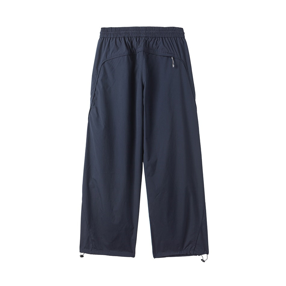 Back view of navy wide-leg trousers with an elastic waistband, curved zip pocket, and adjustable hems.