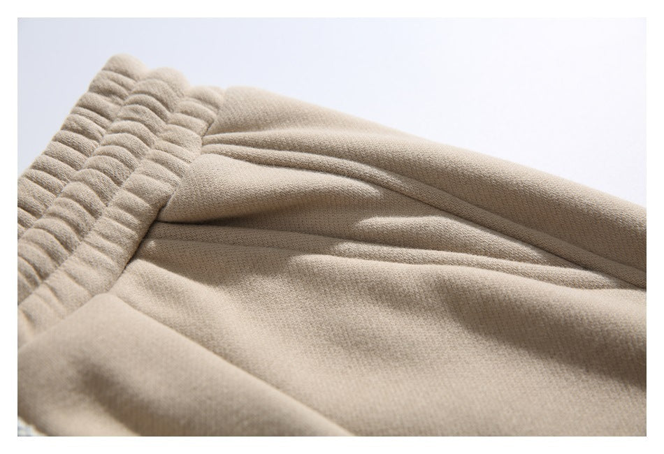 Close-up of beige jogger pants showing the elastic waistband and stitched fabric folds.