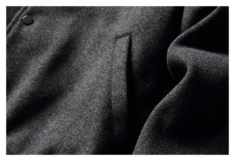 Close-up of the charcoal jacket's vertical welt pocket, textured fabric, and a black snap button.