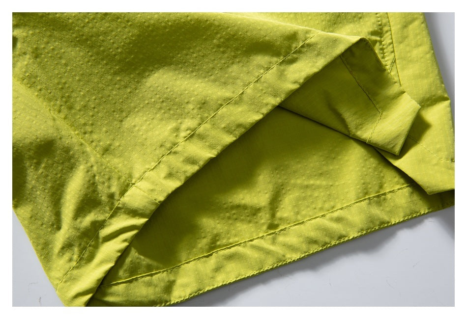 Close-up of the stitched hem and folded fabric edge on lime-yellow shorts.