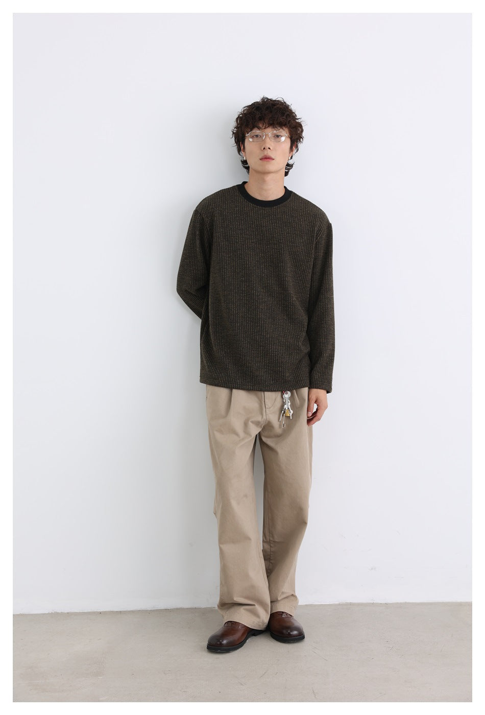 Full-length front view of a model wearing a dark brown subtly striped long-sleeve shirt with a black crew neck.