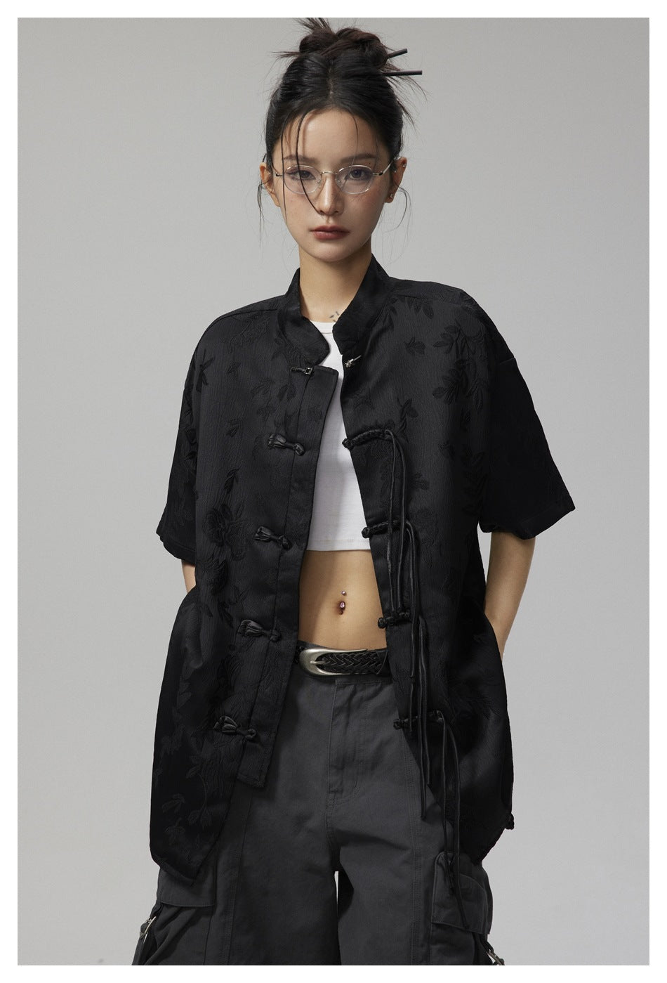 Closer view of a model wearing a black floral jacquard shirt with a stand collar and frog closures.