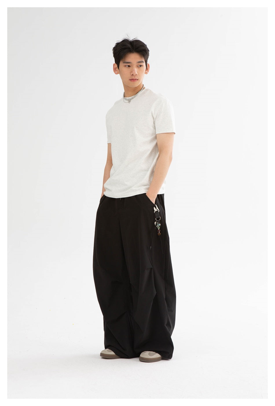 Model in a light heather-gray crew-neck T-shirt and very wide black pants, shown at a three-quarter angle.