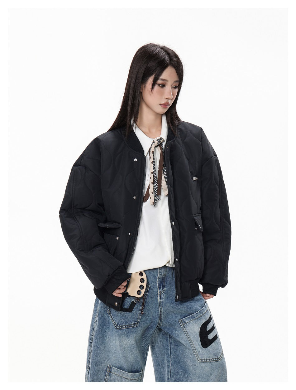 Closer view of a model wearing a black quilted bomber jacket with a ribbed collar, snap front and flap pockets.