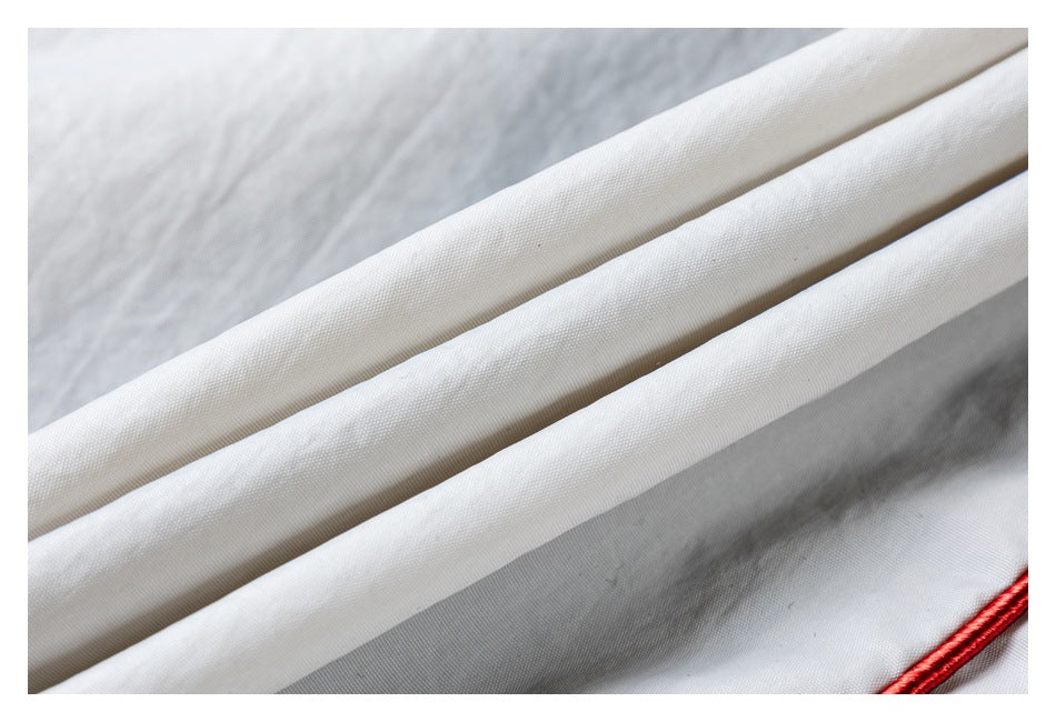 Close-up of folded white fabric with red piping along the edge.