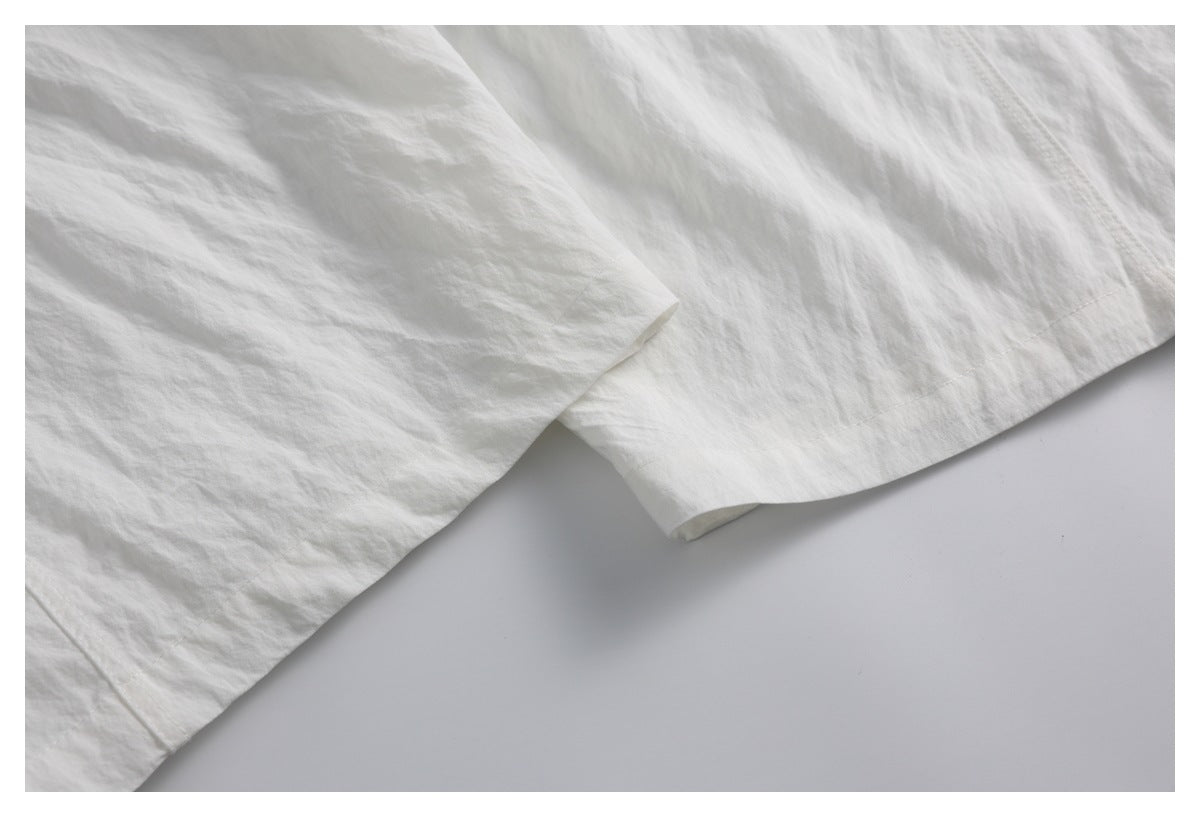 Close-up of the white garment’s stitched hem and overlapping fabric edges.
