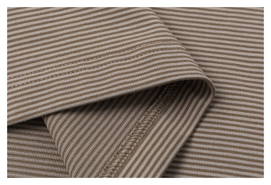 Close-up of a folded edge and overlocked seam on beige and brown striped fabric.