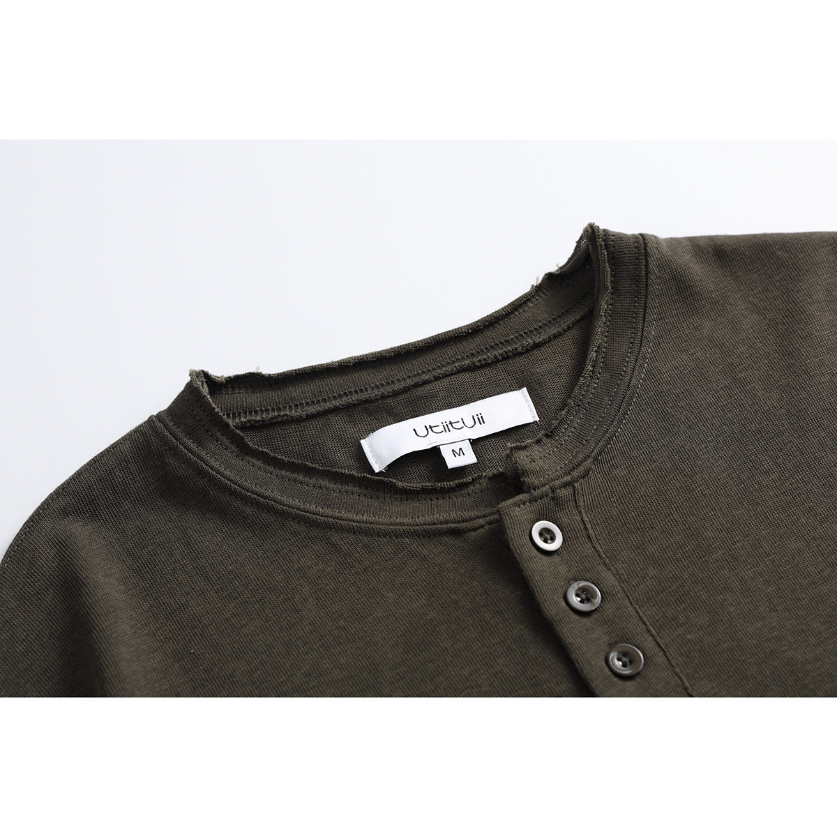 Close-up of a dark olive Henley shirt's crew neckline, three-button placket, and sewn-in label.