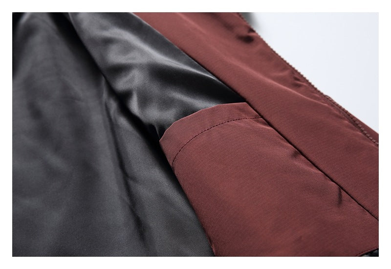 Close-up of a burgundy jacket pocket and seam beside its dark lining.