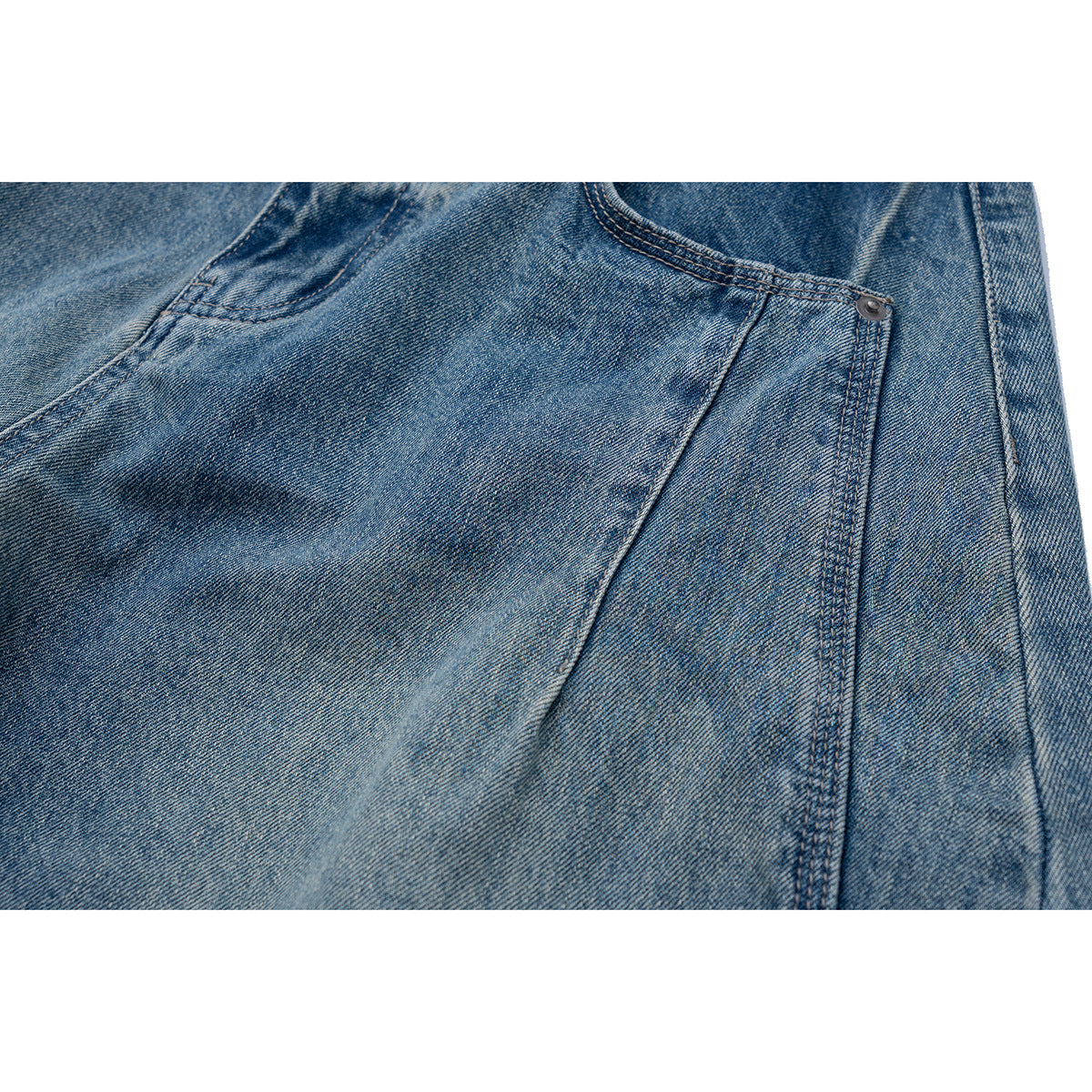 Close-up of a front pocket and rivet on faded blue jeans.