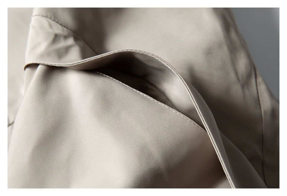 Close-up of a curved pocket opening with a narrow piped edge on beige fabric.