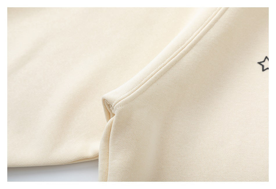 Close-up of a seam on cream sweatshirt fabric, with part of a small black star print at the edge.