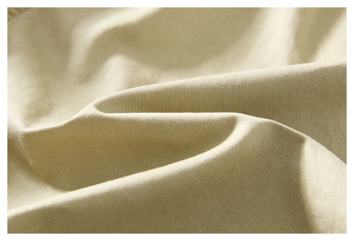 Macro view of beige garment fabric showing its fine diagonal weave and soft folds.