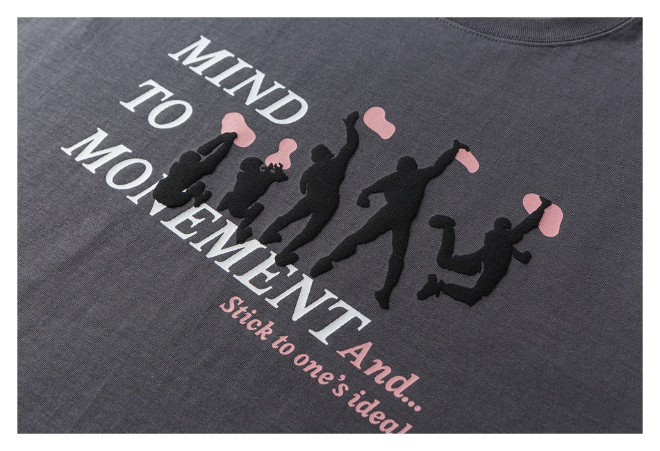 Close-up of a charcoal T-shirt print with white lettering, pink accents, and black silhouettes of people.