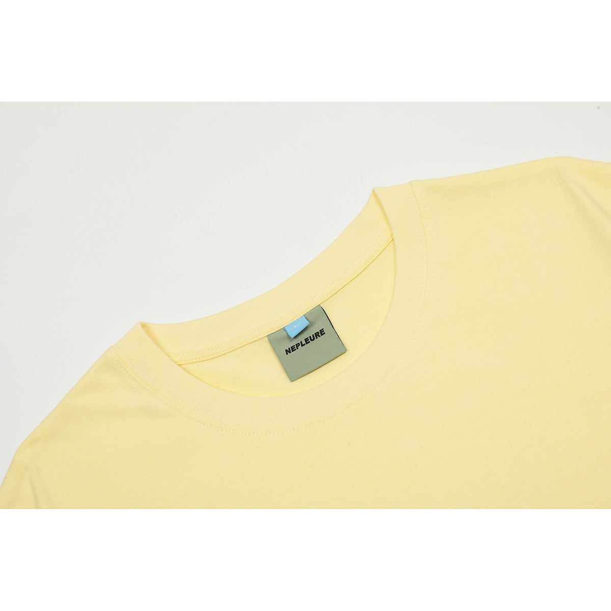 Close-up of the pale yellow T-shirt crew neck and attached label.