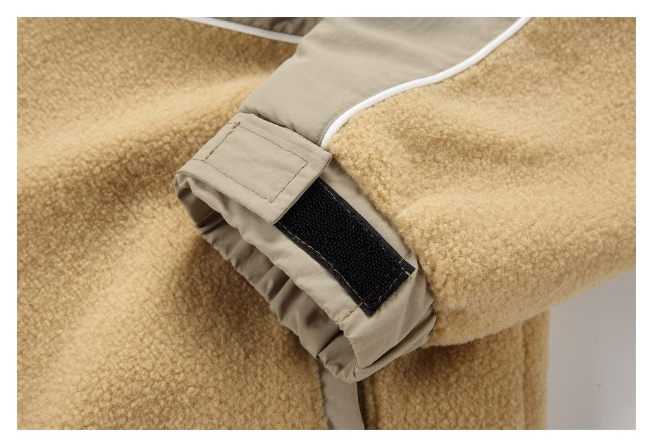 Close-up of a beige coat cuff with a black hook-and-loop tab and white piping beside tan fleece.