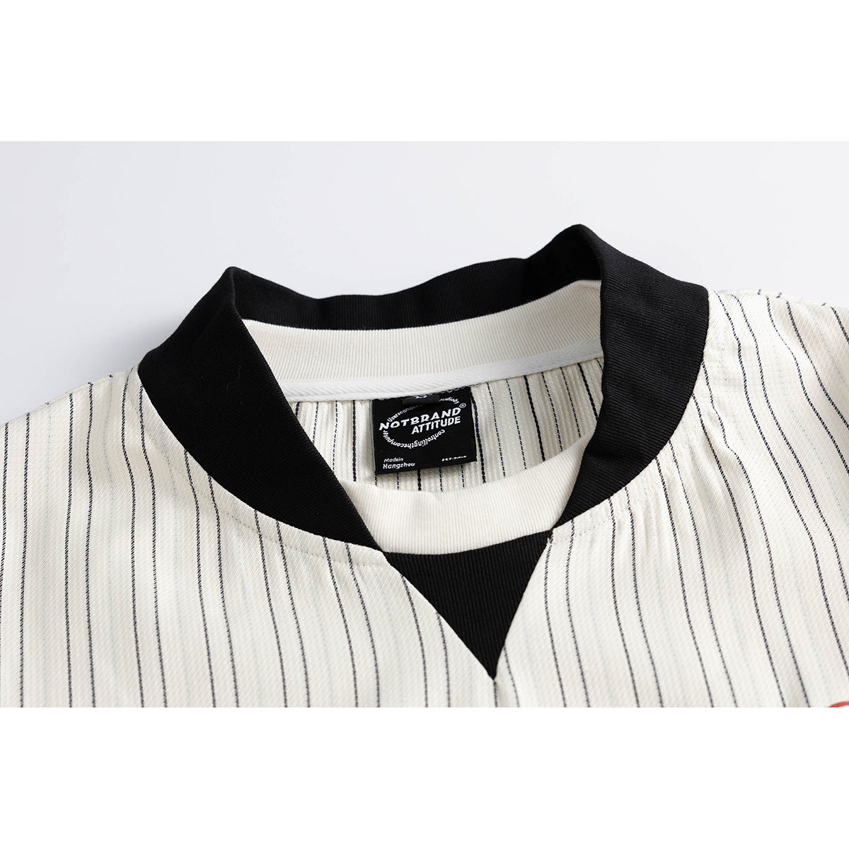 Close-up of a cream pinstriped jacket's black ribbed collar and inner neck label.