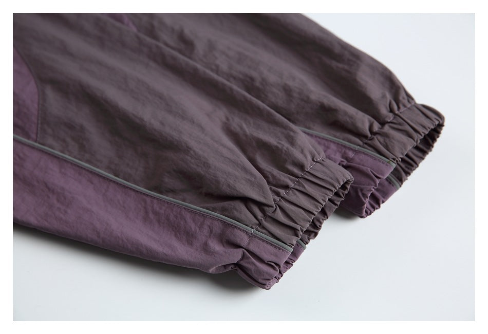 Close-up of plum garment legs with elasticated cuffs and gray piping.
