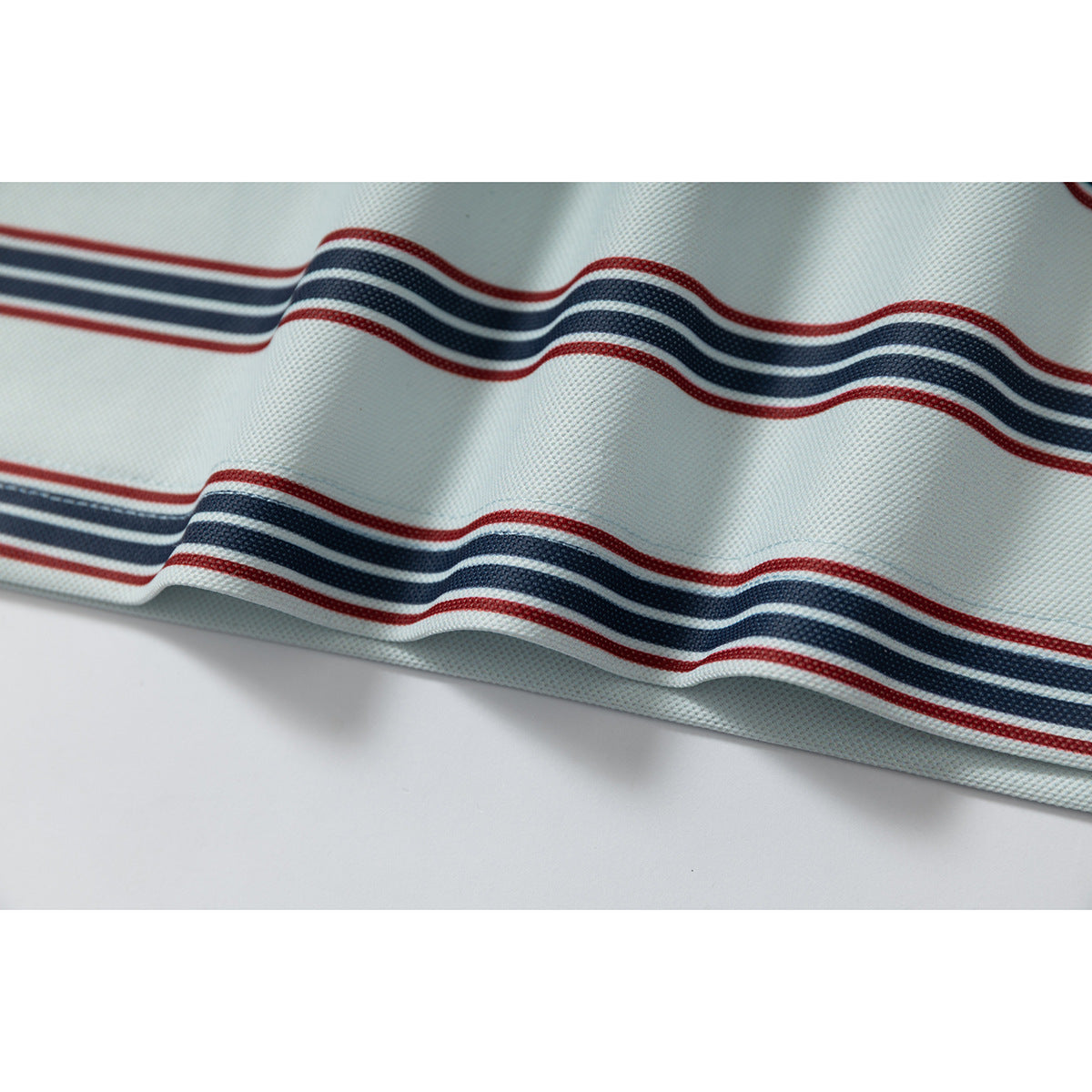 Close-up of pale mint knit fabric with wavy navy and red stripes.