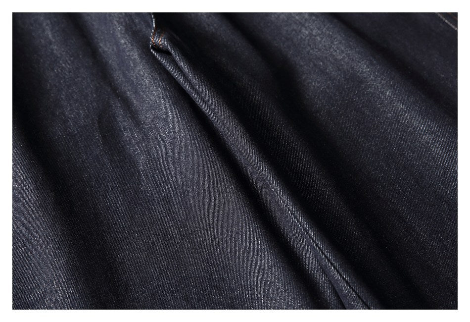 Close-up of dark denim fabric with a diagonal stitched seam.