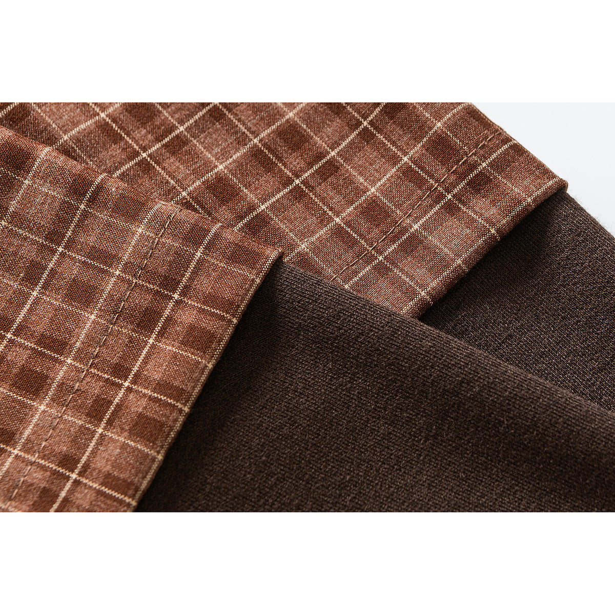 Close-up of brown plaid shirt fabric and seams beside a dark, textured fabric panel.