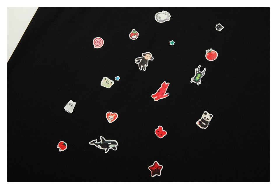 Close-up of colorful small character, fruit, animal, and star patches scattered across black fabric.