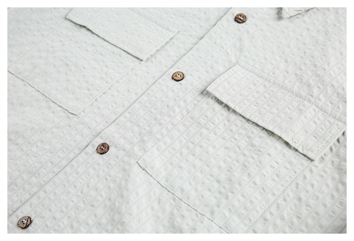 White shirt front with two chest pockets, brown buttons, and a textured vertical stripe pattern.