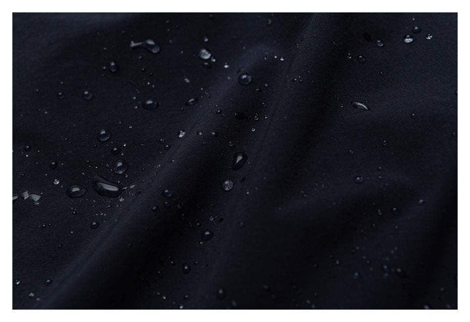Close-up of water droplets beading on black fabric.