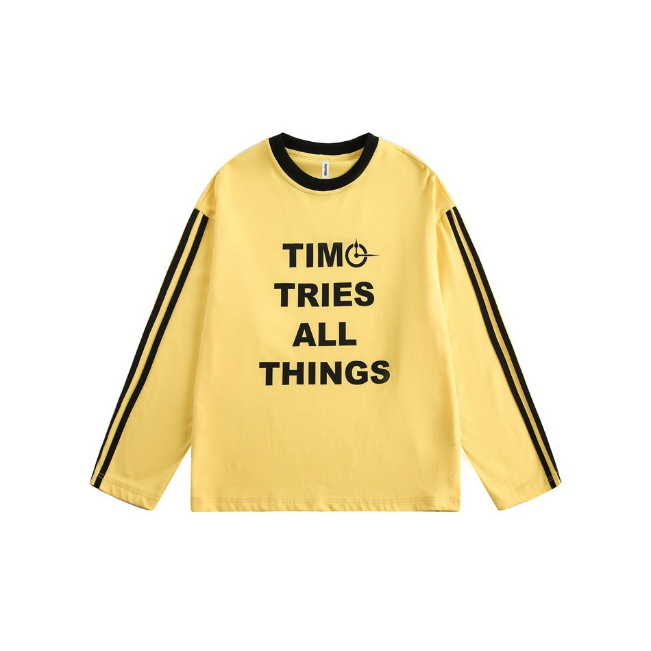 Yellow long-sleeve crewneck top with black collar, black sleeve stripes and black TIMO TRIES ALL THINGS print, flat lay