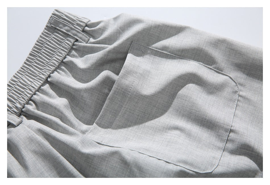 Close-up of light gray shorts with an elastic waistband and a large rectangular patch pocket.