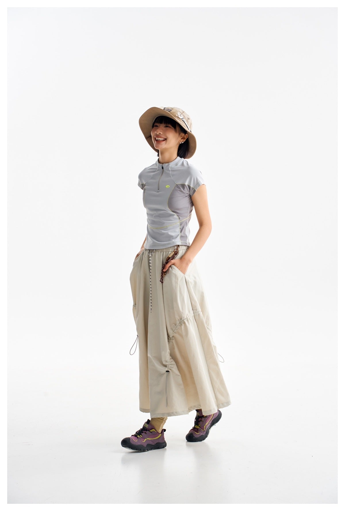Model in a pale gray paneled quarter-zip top and long cream skirt, shown at an angle.