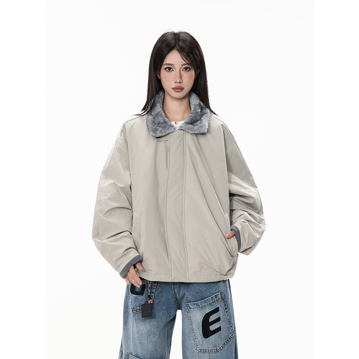 Front view of a model wearing a light gray oversized jacket with a gray plush collar and blue patchwork jeans.