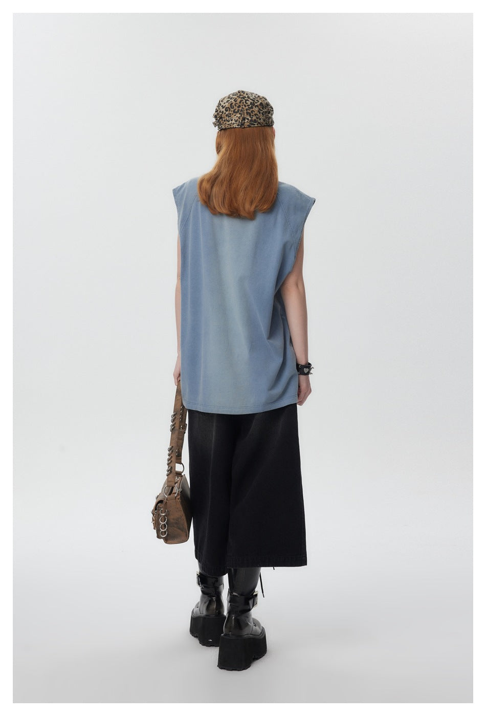 Full rear view of a model wearing a faded blue sleeveless shirt with a loose, long fit.