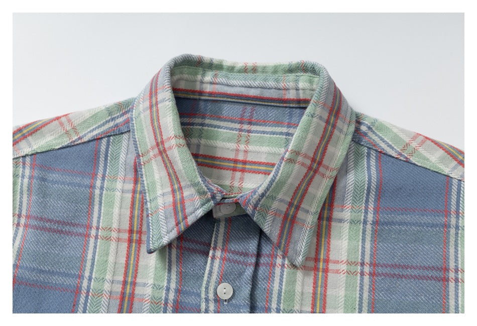 Close-up of the blue plaid shirt's pointed collar, shoulder seams and white front buttons.
