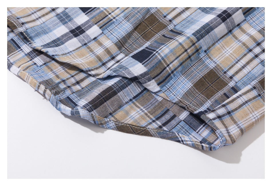 Close-up of the curved hem and stitching on a blue, navy, brown, and white plaid shirt.