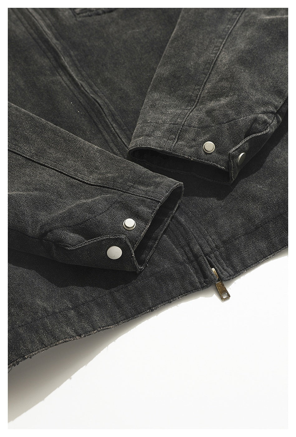 Close-up of a charcoal jacket sleeve cuffs with metal snaps and a zipper hem.
