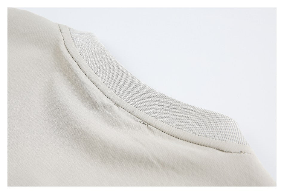 Close-up of a light beige crew neckline with a ribbed collar and visible stitching.