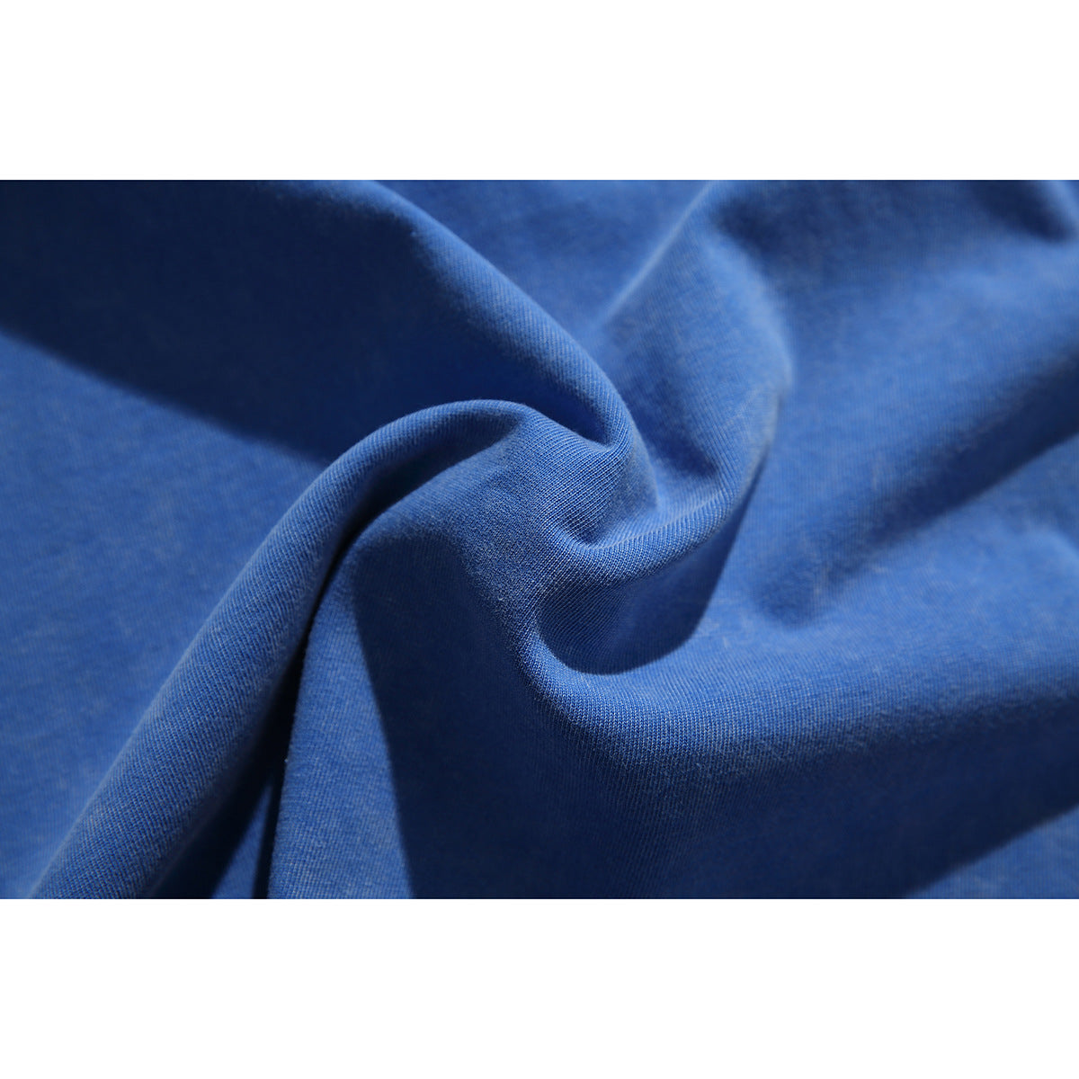 Close-up of blue fabric gathered into folds, showing its surface texture.