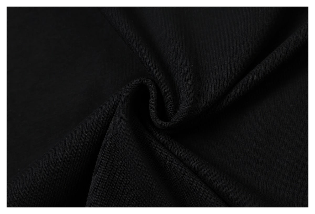 Close-up of black fabric gathered into soft folds, showing its fine knit texture.