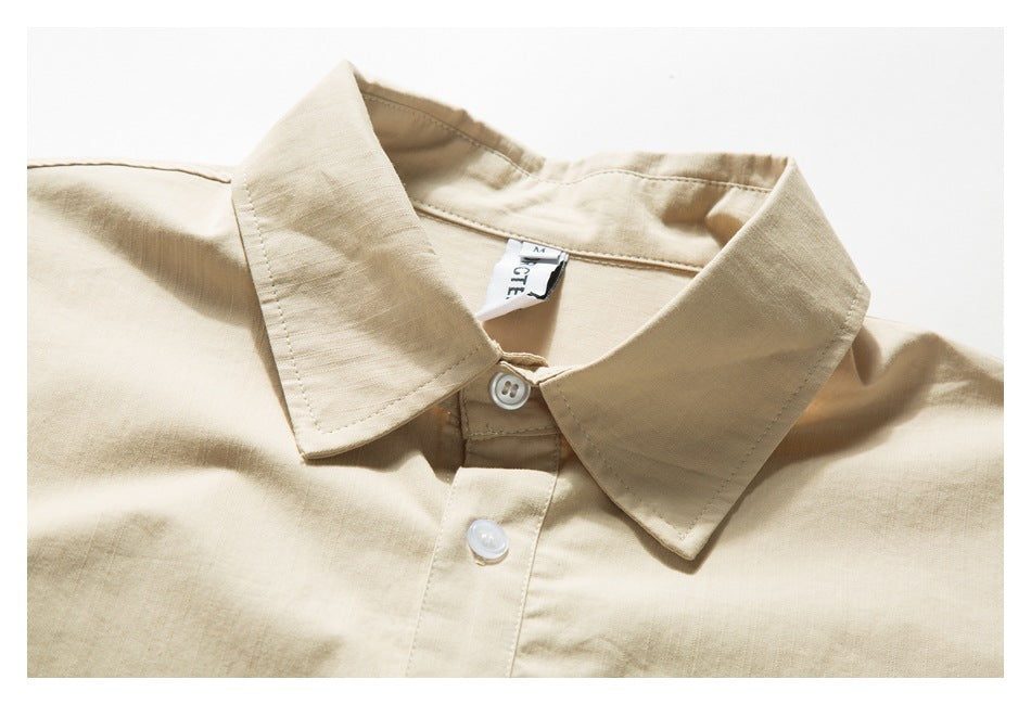 Close-up of a beige shirt collar and white buttons, with a small label visible inside the neckline.